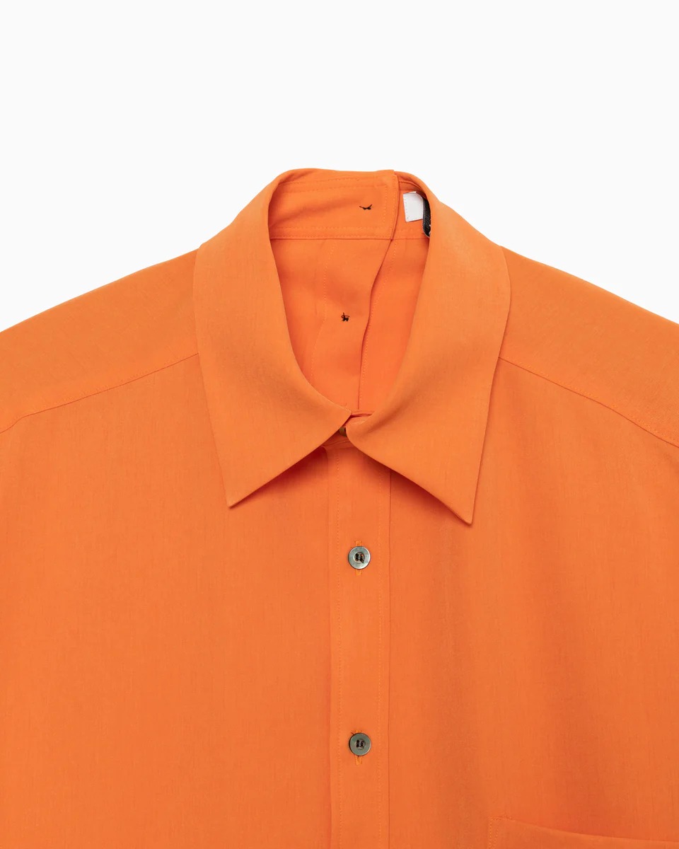 オレンジのボタンが施され自由に開閉できるシャツ