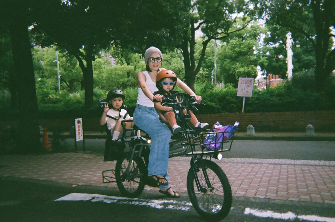 ママチャリに2人の子供と女性が乗る写真