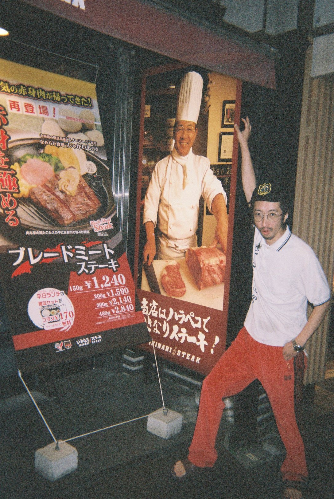 「いきなりステーキ」門前仲町店の前でポーズをとる田中俊行