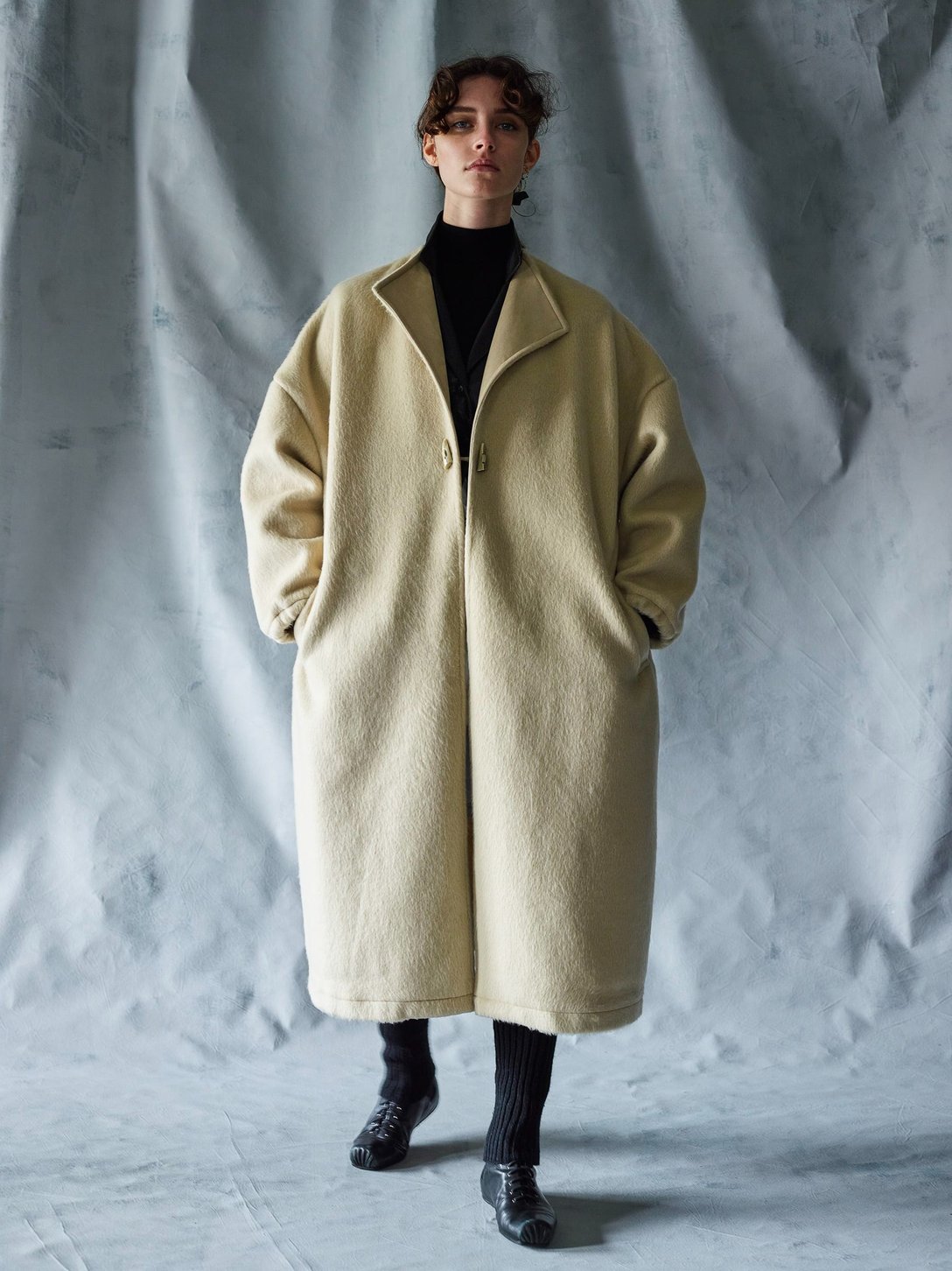 オーバーサイズのベージュのコートを着たモデル
