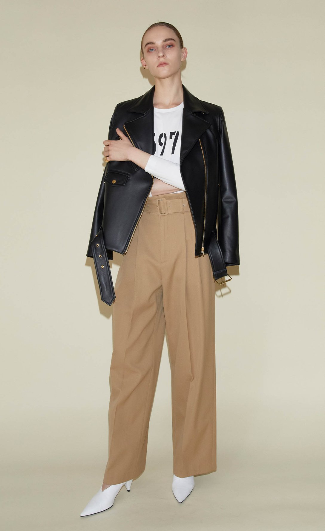 ライダースジャケットとベージュのパンツを着用した女性モデル