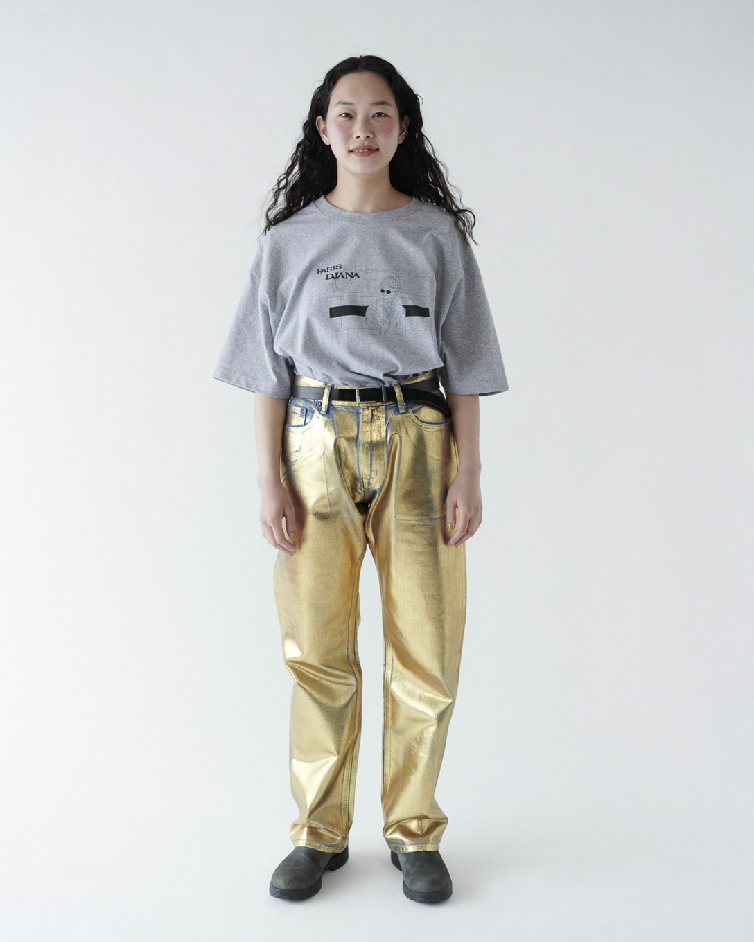 グレーのTシャツにゴールドカラーのデニムを着用した女性モデル