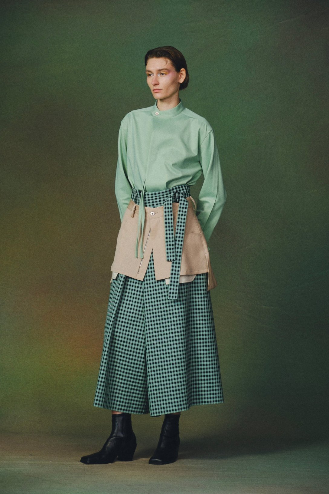 グリーンのブラウスにグリーンチェックのスカートを合わせた女性モデル
