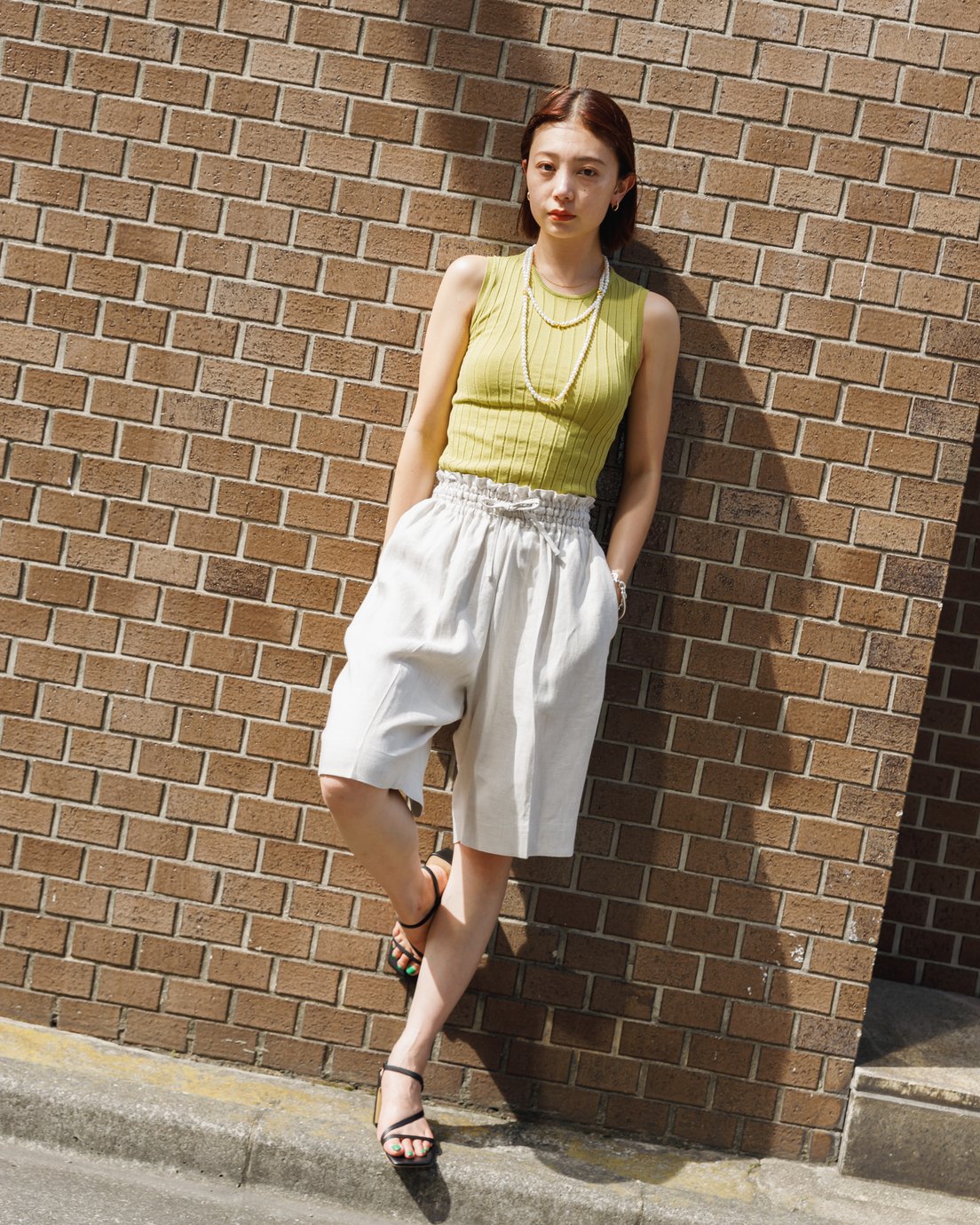 イエローのリブタンクに白のリネンショーツを合わせた女性モデル