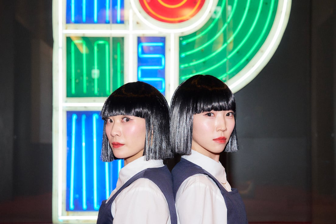 背中合わせでPのネオンサインの前に座るsonoとpani