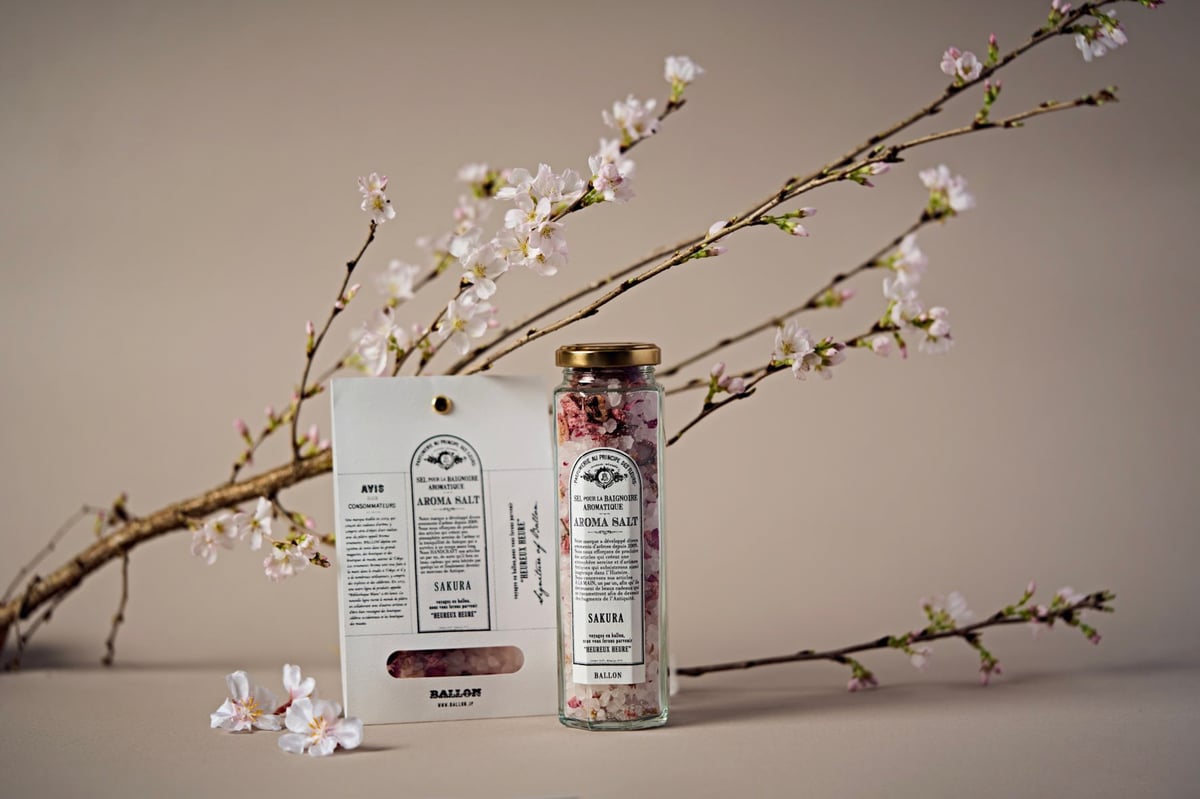 花が咲いた桜の切り枝とバスソルトの商品ボトルを映した写真