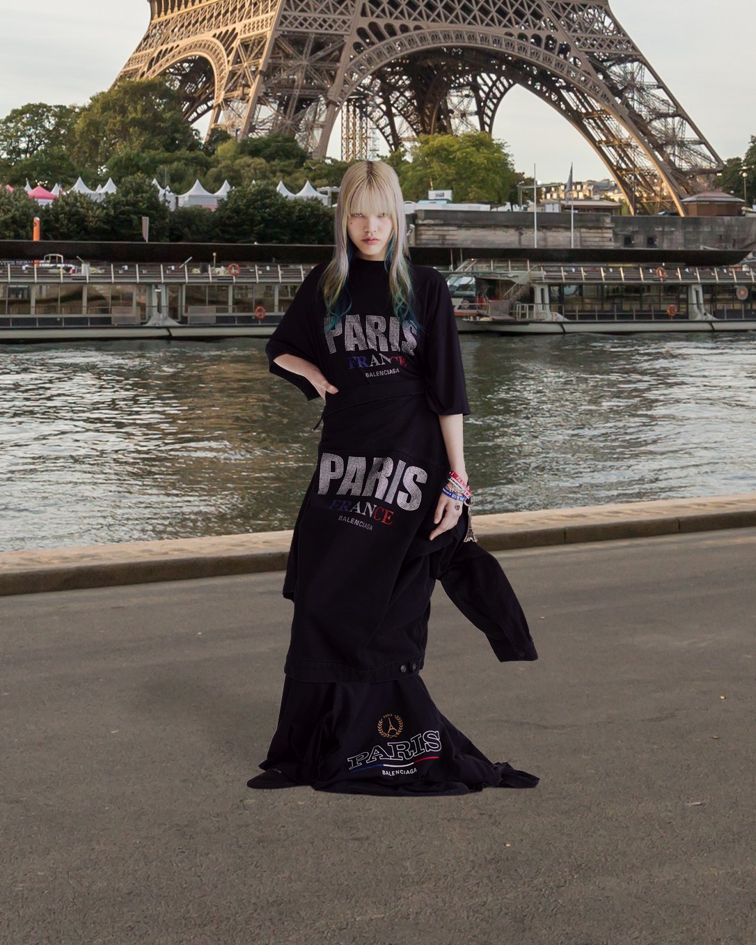 「PARIS」のプリントが入ったTシャツを着てエッフェル塔の前でポーズを撮る女性モデル