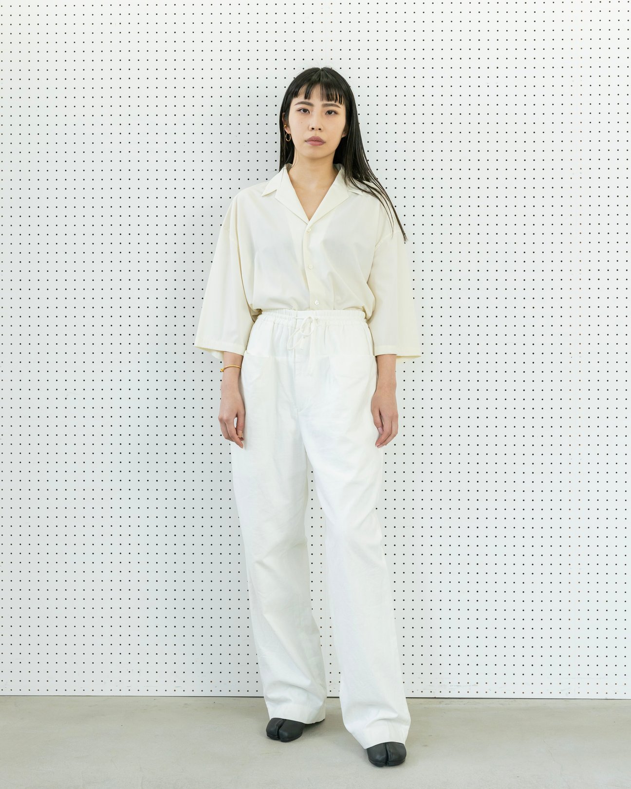 白いシャツに白いワイドパンツを着用した女性
