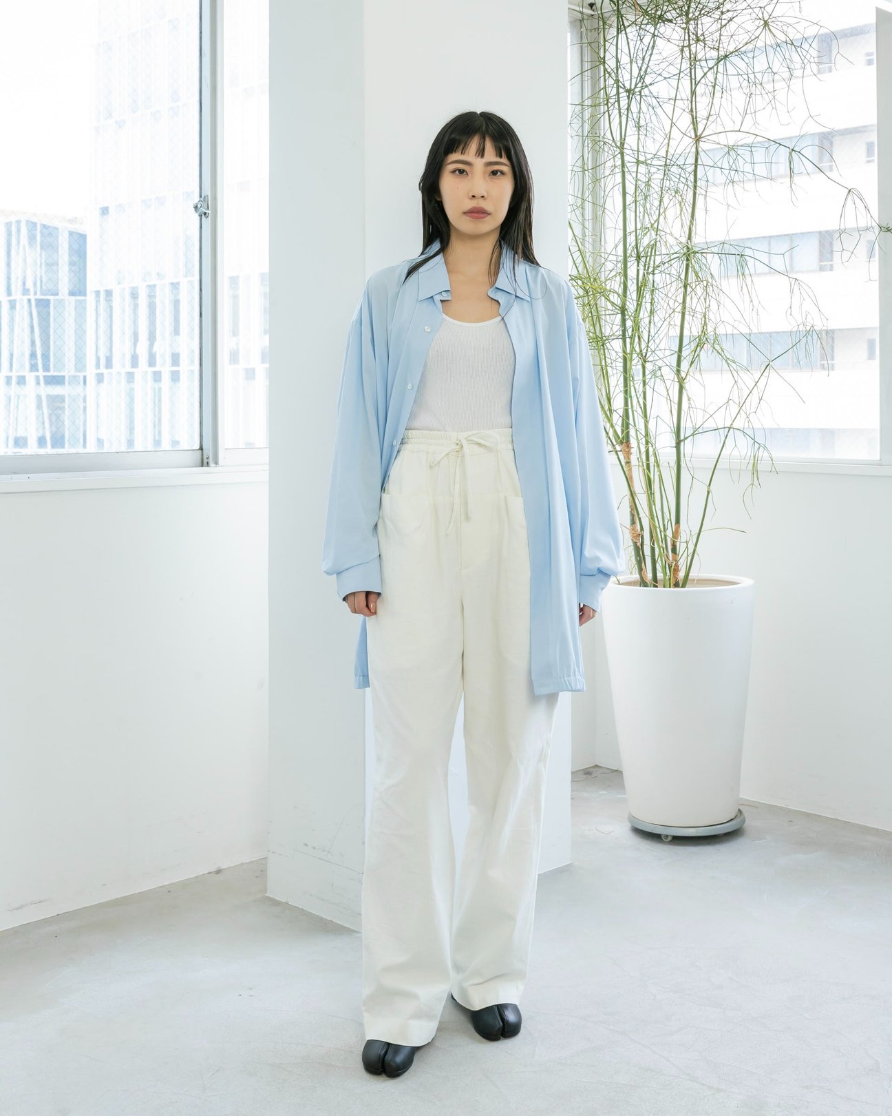 青いシャツに白のパンツを穿いている女性