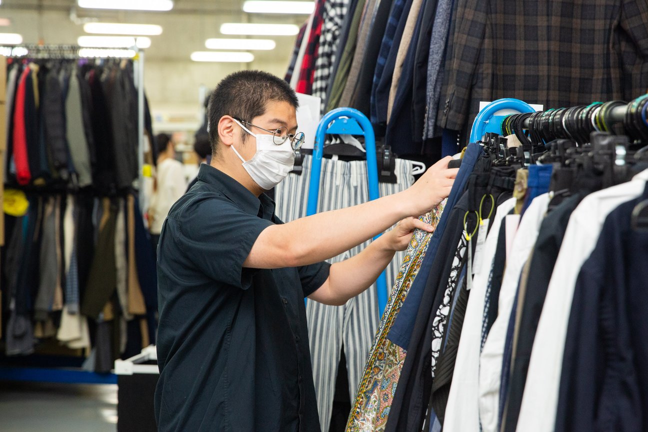 ラックに掛けられた服を選ぶ男性