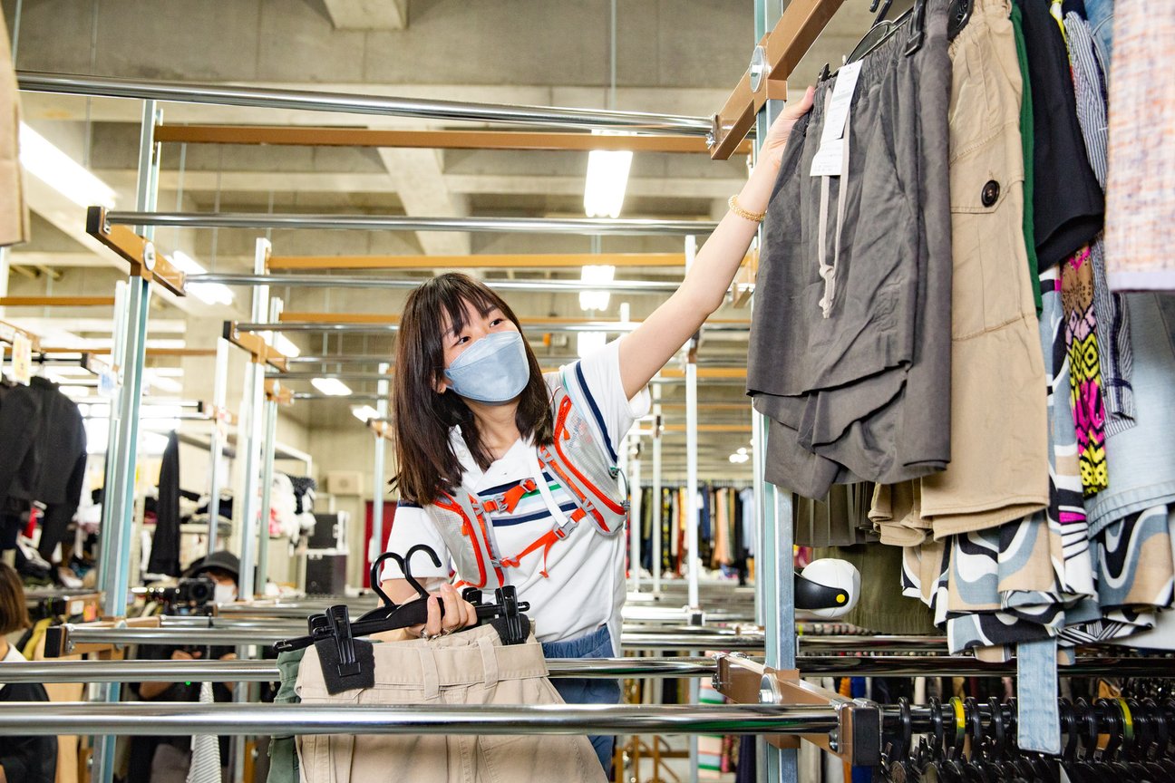 ラックに掛けられた服を選ぶ女性