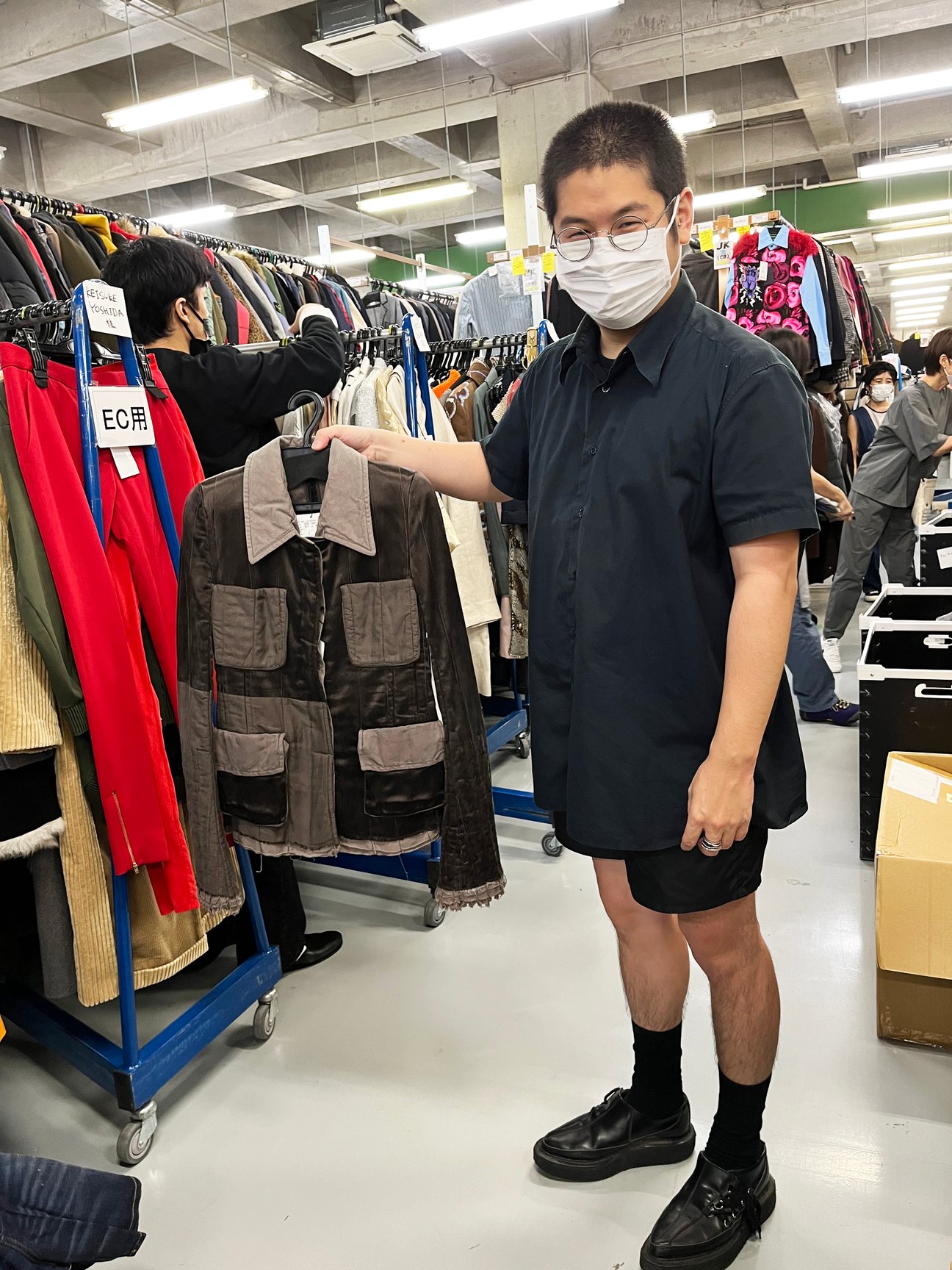 ブラウンのアウターを手に持った男性