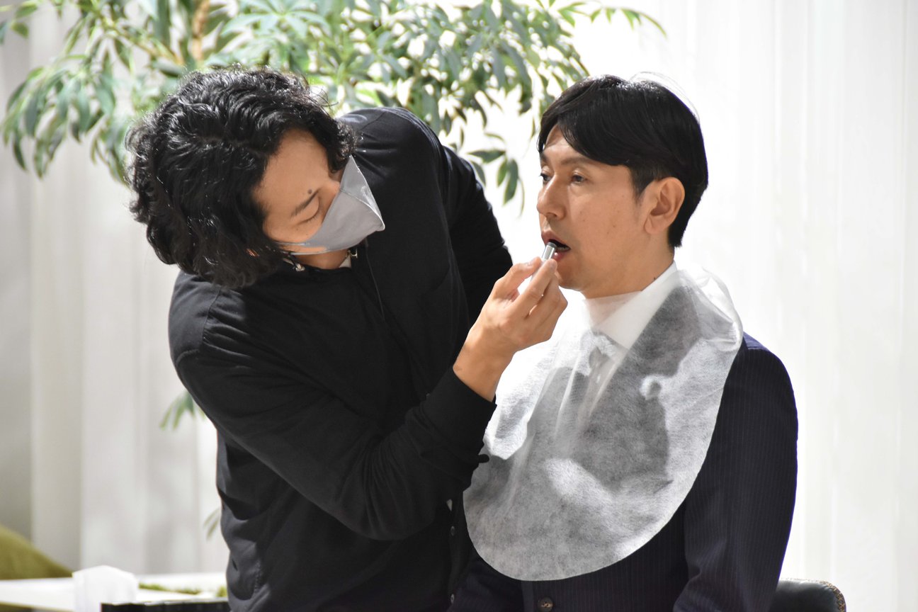 リップを塗るメンズメイクアーティストとスーツの男性