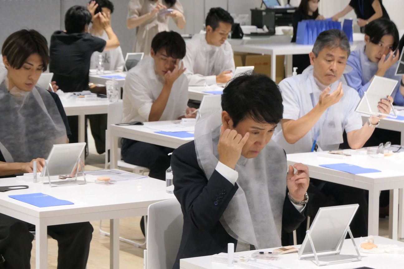 鏡を見ながらアイメイクをする男性