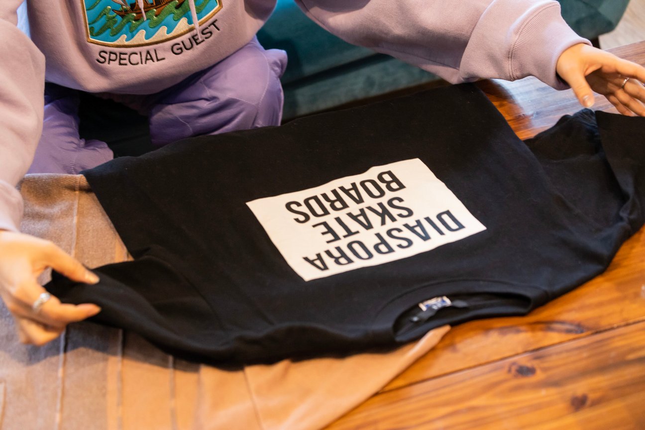 「ディアスポラ スケートボーズ」のロゴを配した黒いTシャツ