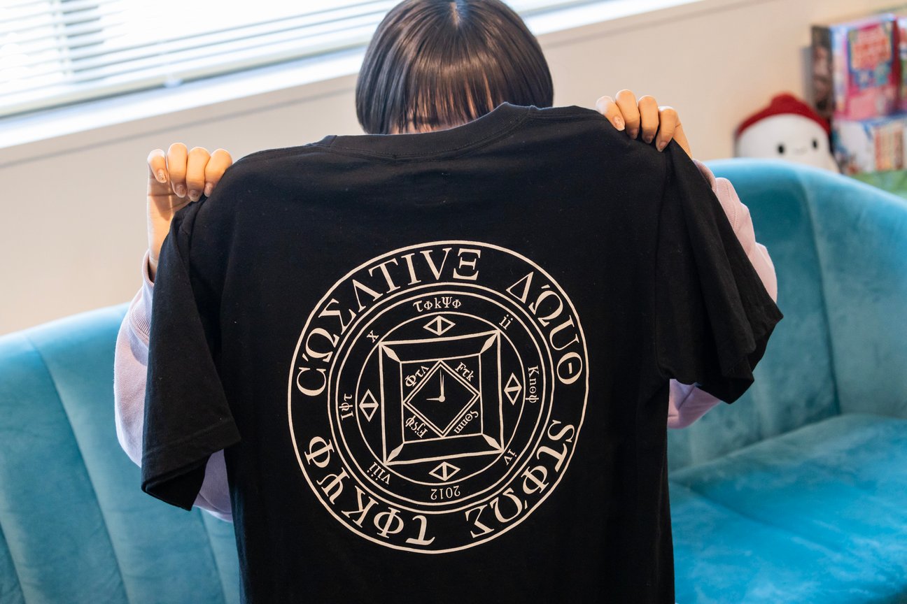 「クリエイティブドラッグストア」のロゴを後ろに配した黒いTシャツ