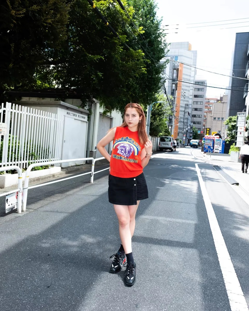 バンドTシャツのデザインが施されたニットベストを着た女性