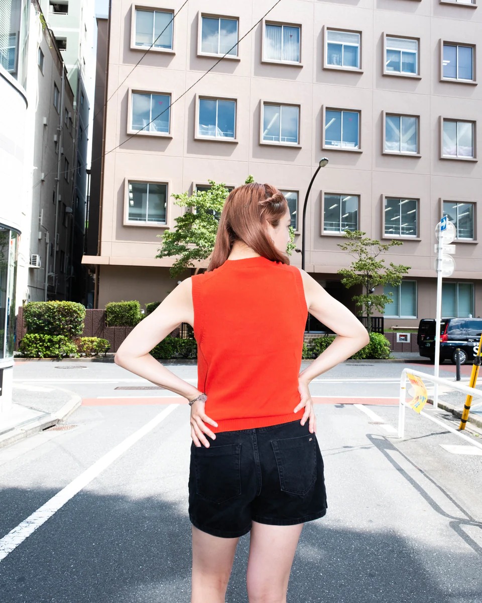 バンドTシャツのデザインが施されたニットベストを着た女性