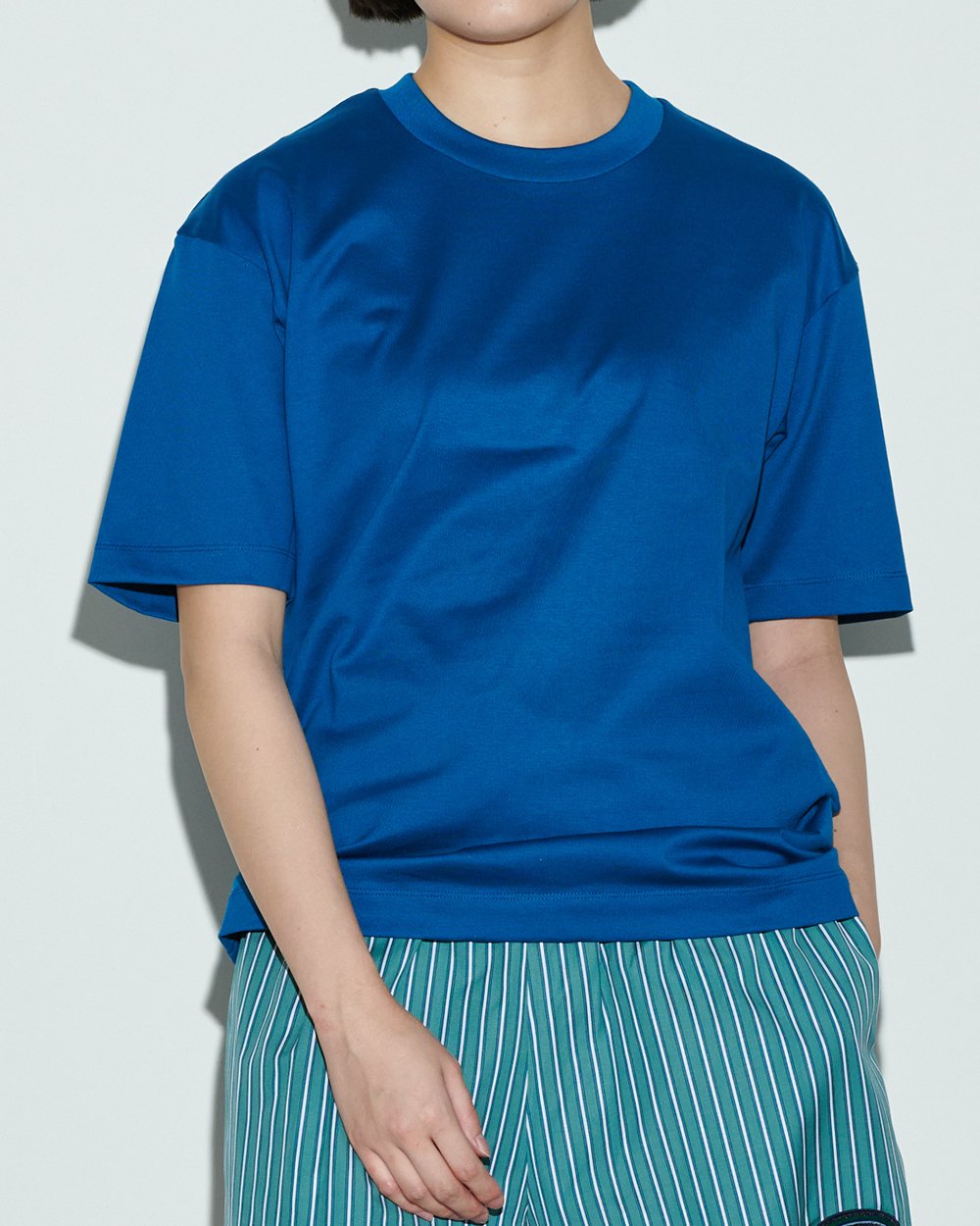 チノのブルーのTシャツを着用した女性モデル