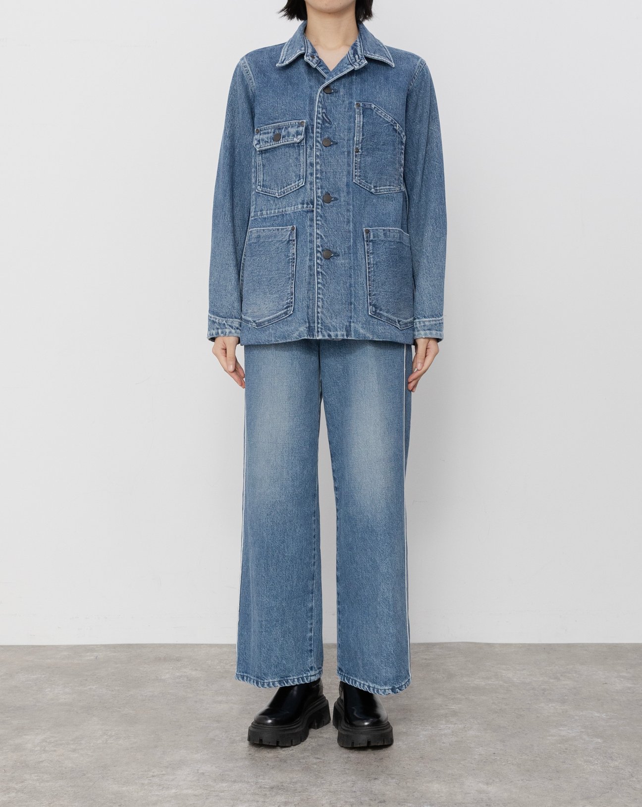 デニムジャケットとパンツのセットアップを着用した女性。