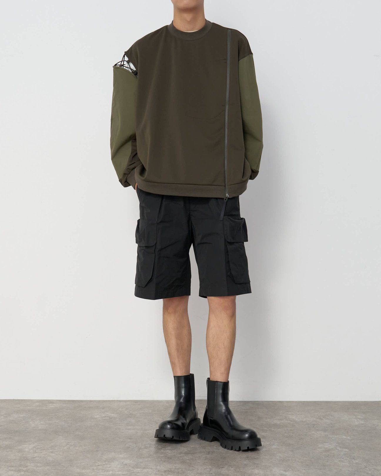 カーキのパーカーとハーフパンツのスタイリングを着用した男性。