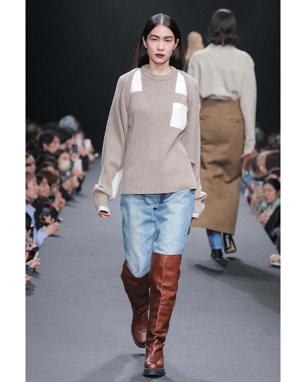 デニムとニーハイブーツとのスタイリングを着用した女性。