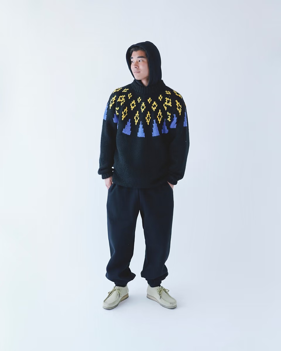 セーターとスェットパンツのスタイリングをした男性。