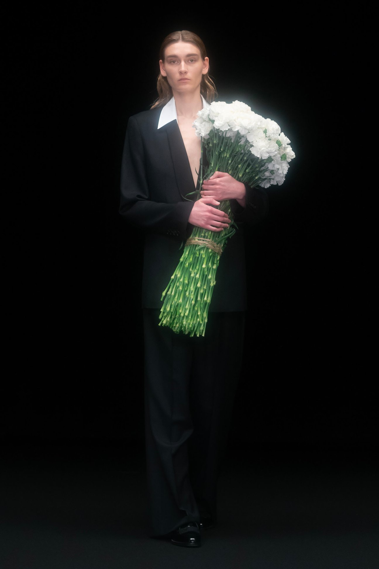 黒いスーツを着て花束を持った男性