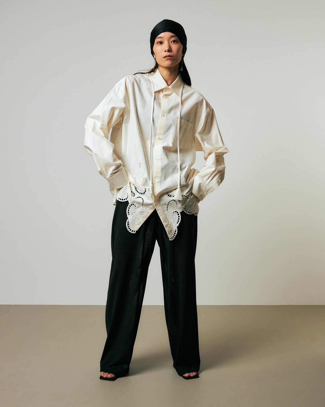 白のブラウスにブラックのシアーパンツを合わせた女性モデル