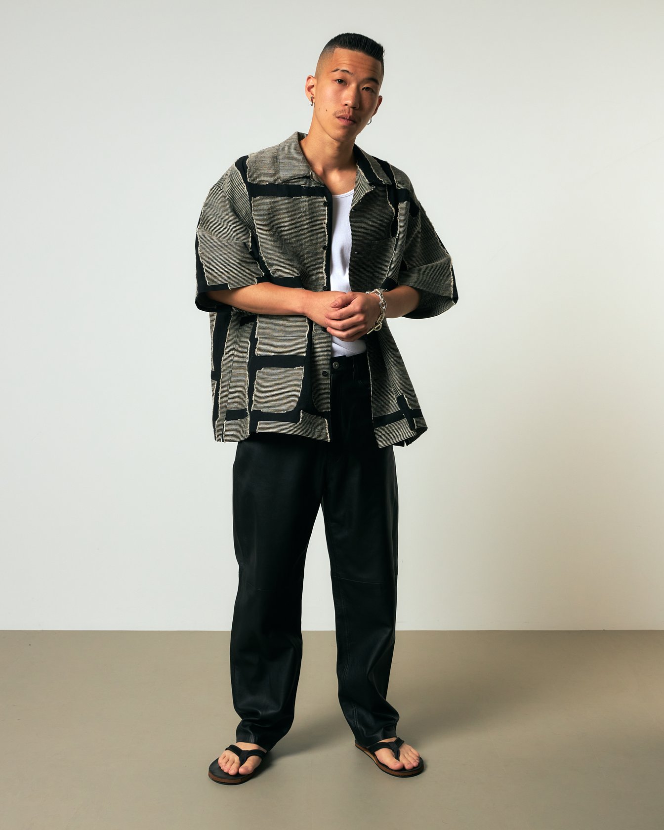 ジャカードシャツにブラックのスラックを合わせた男性モデル「