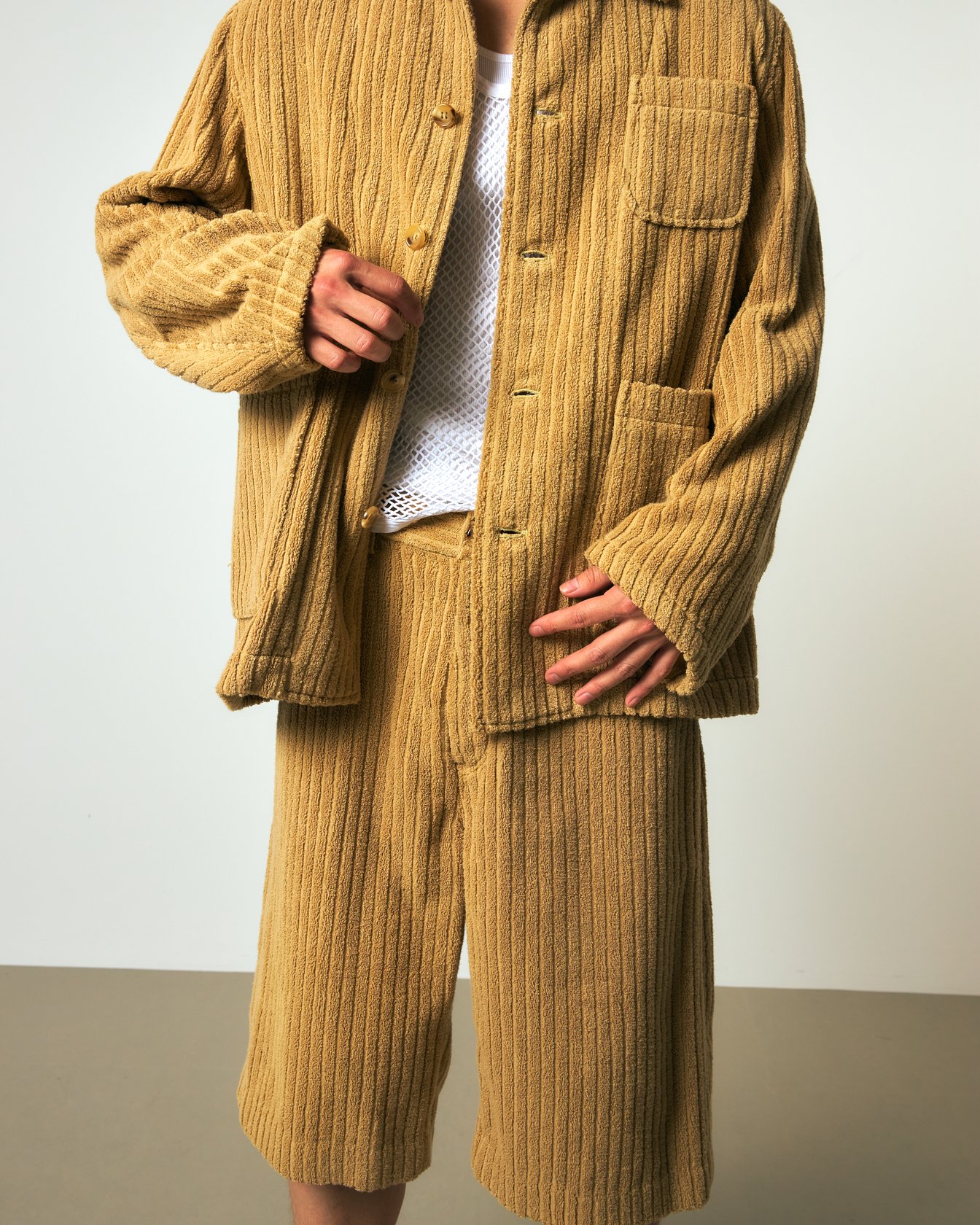 ベージュのパイルジャケットとパンツのセットアップを着た男性モデル