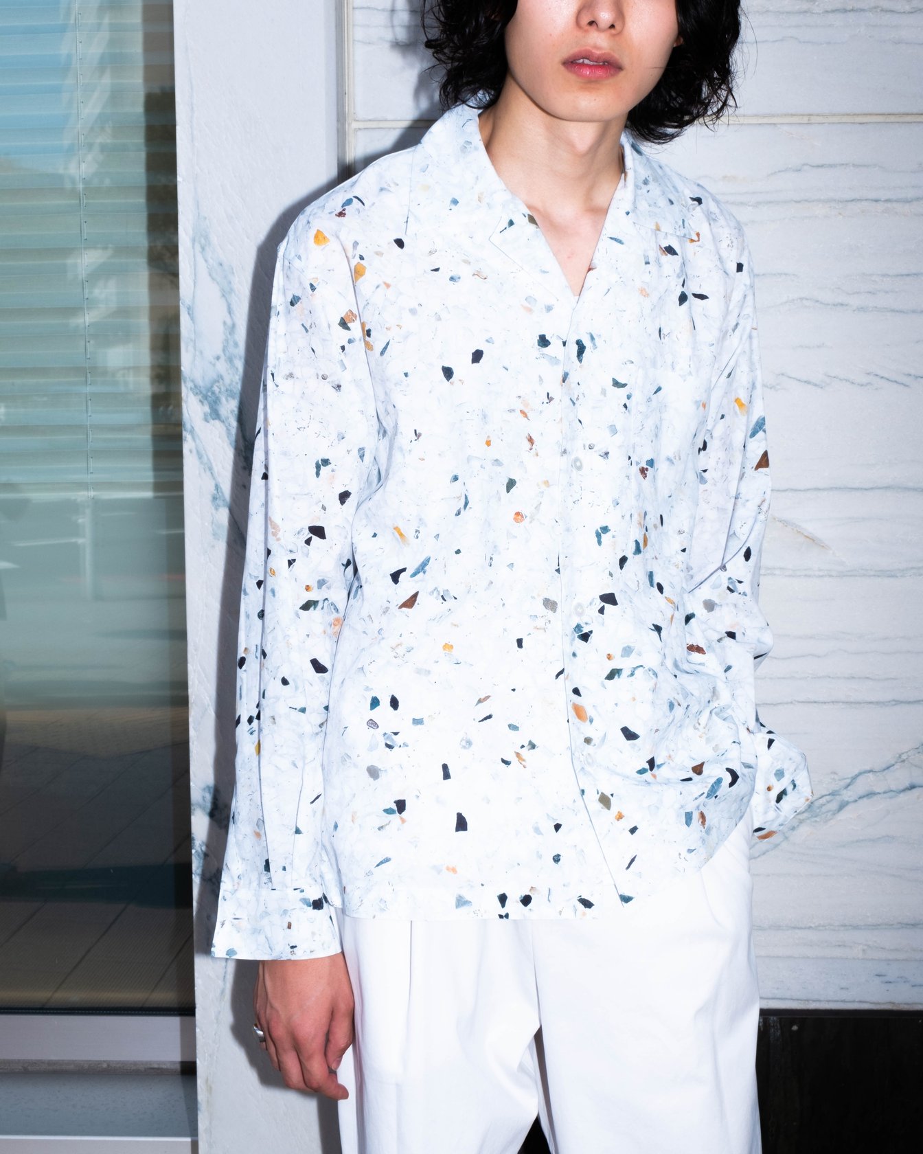 白の柄シャツに白いパンツを合わせた男性モデル