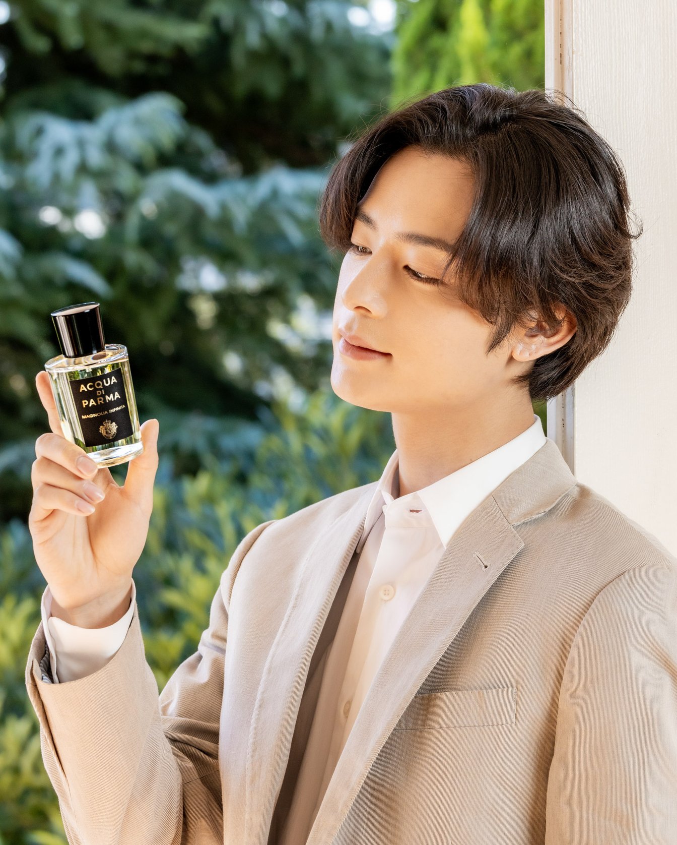 香水を手に持つジャケットを着た男性