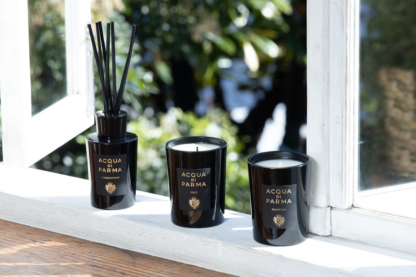 白い窓枠の上に並んだ黒い容器のディフューザーとキャンドル 