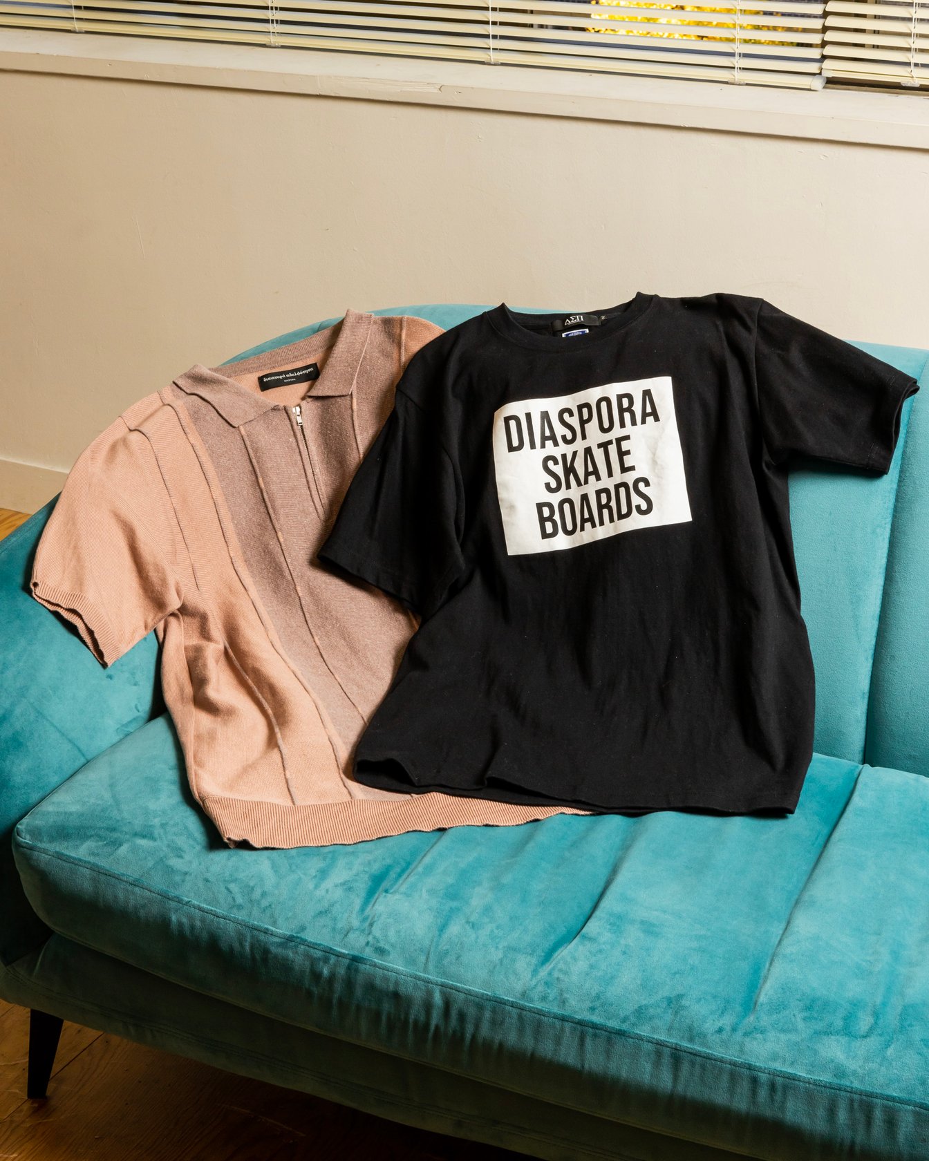 ピンクのポロニットと「ディアスポラ スケートボーズ」のロゴを配した黒いTシャツ
