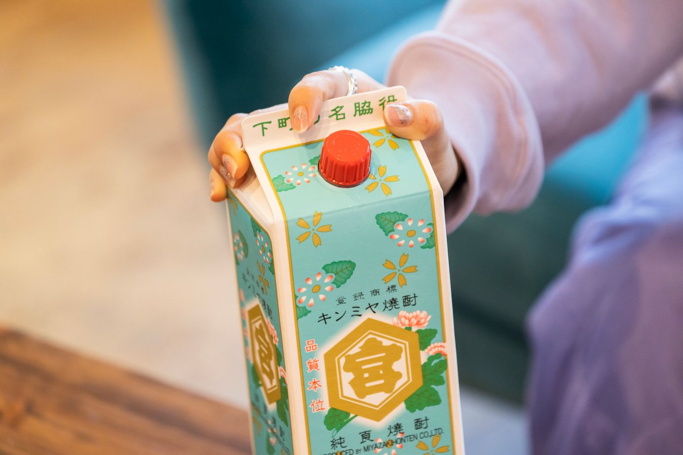 水色のパッケージのキンミヤ焼酎を持つサーヤの手元