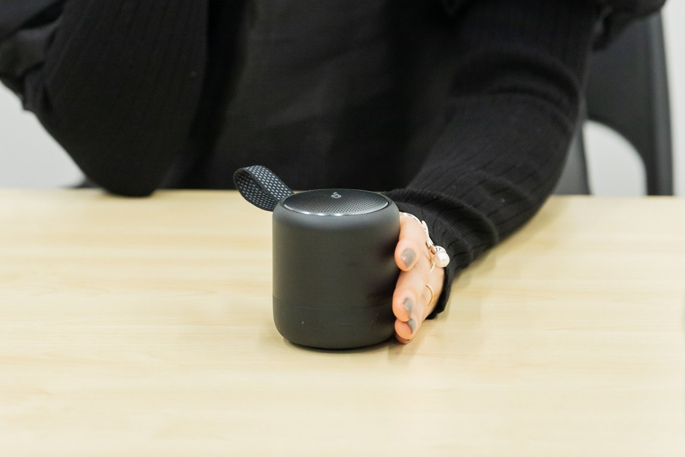 黒いコンパクトなスピーカーを手に持っている女性