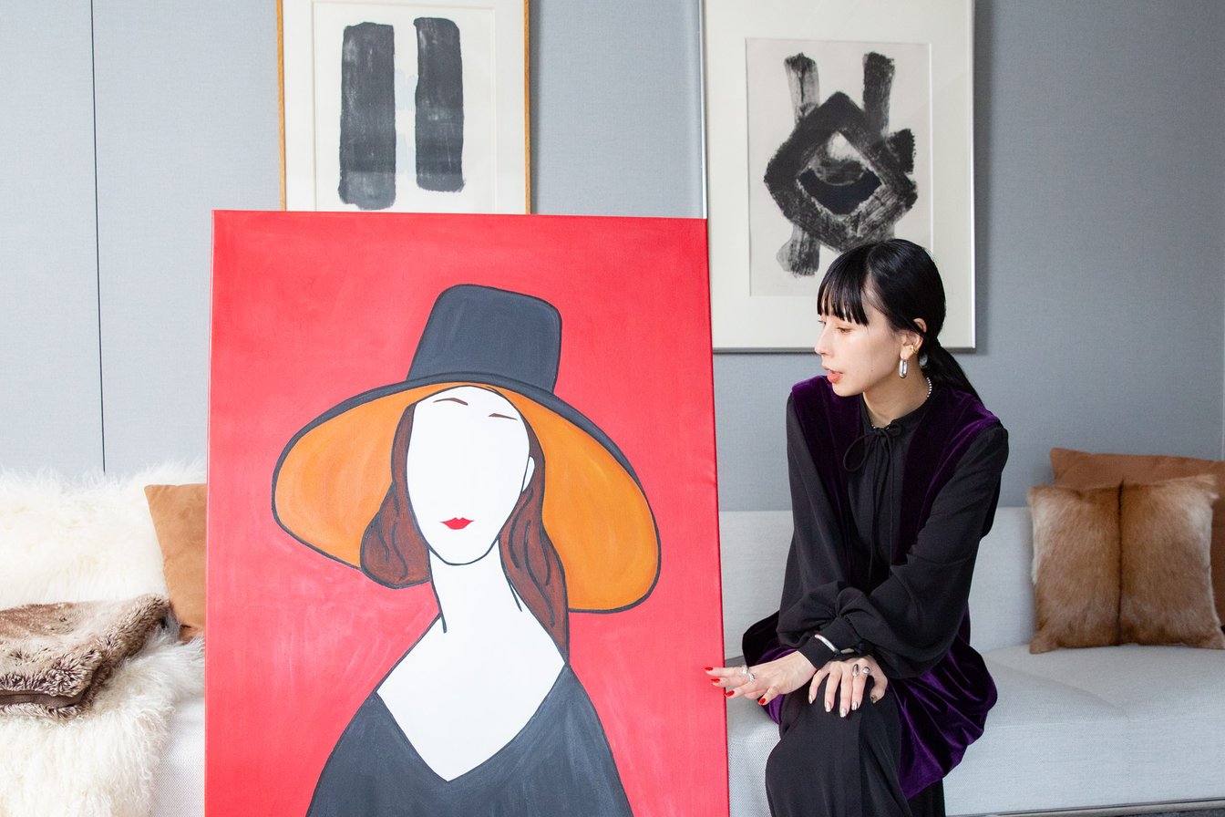 赤いアート作品を脇に話す黒石