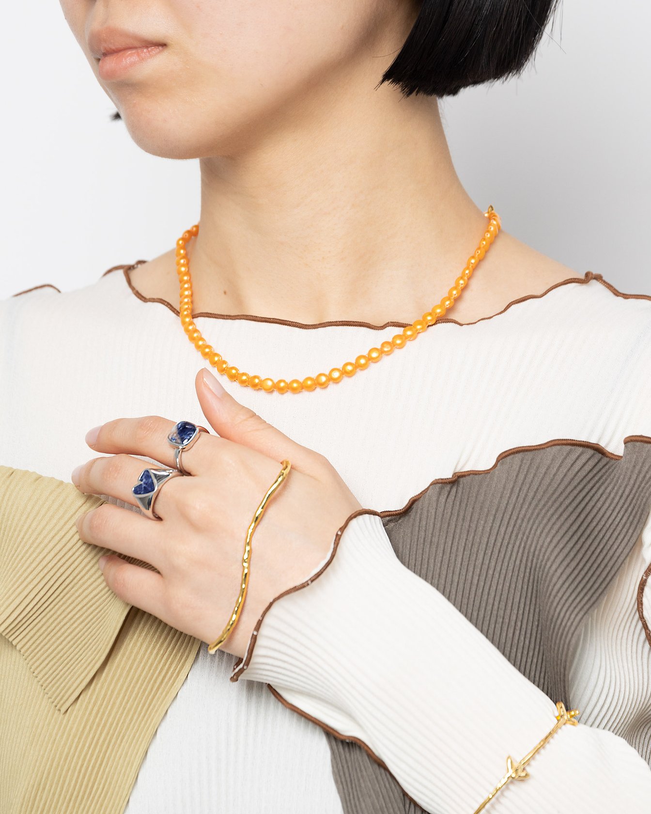 オレンジのパールネックレスを身につけた女性モデル