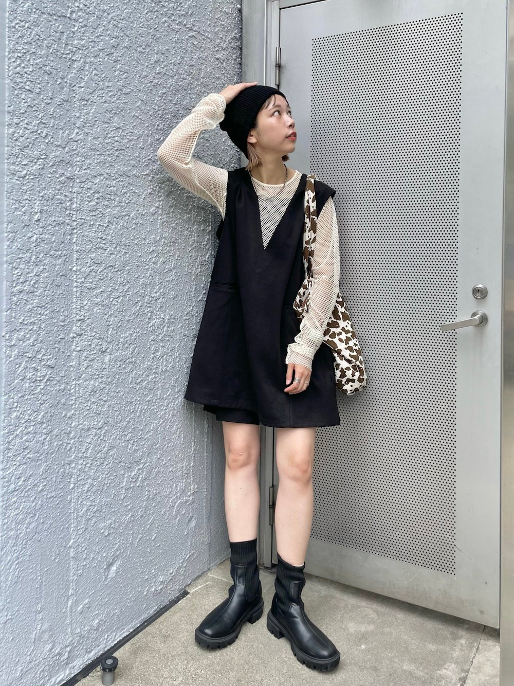 黒いワンピースとベージュのカットソーを着用した女性