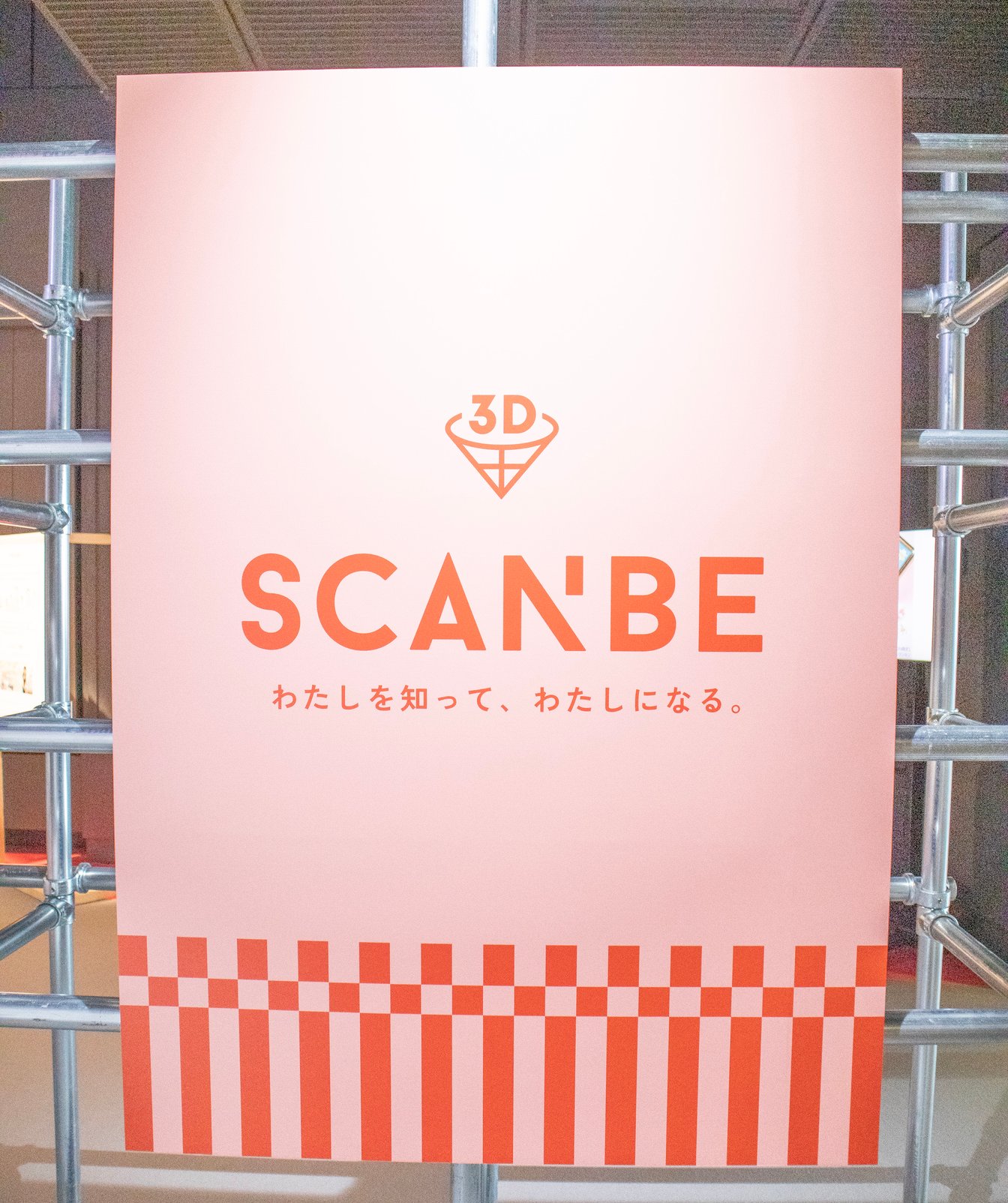 ピンクを背景にした「スキャンビー」の赤いロゴ