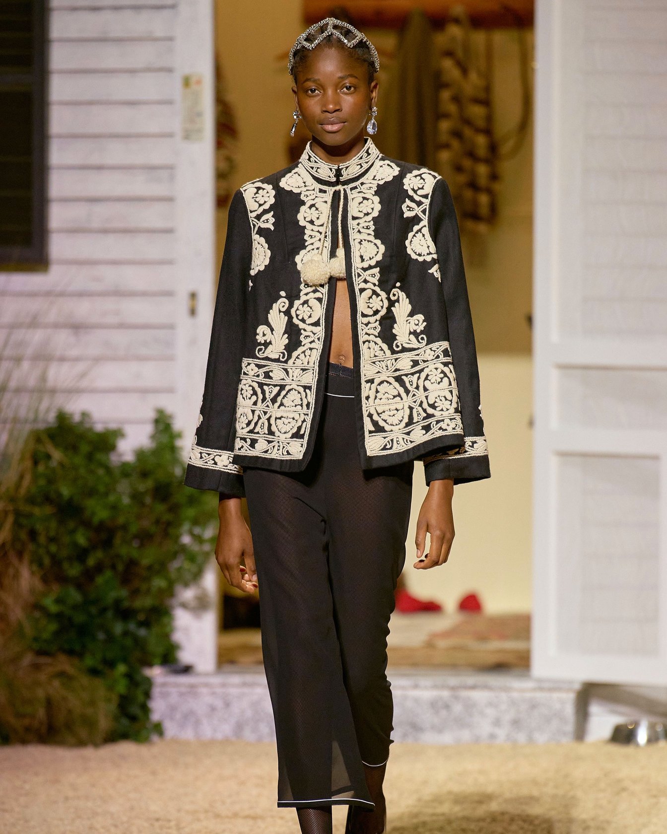 装飾が施されたウェアを着てランウェイを歩く女性