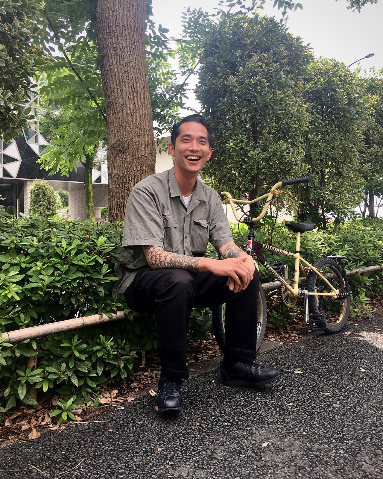 街路樹の前に座る山本海人氏