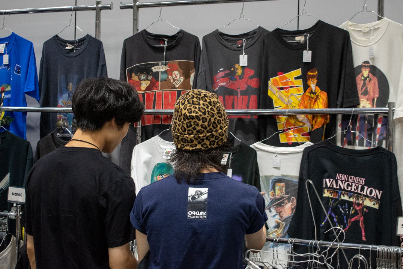 ラックに陳列された古着のTシャツを見る2人の男性