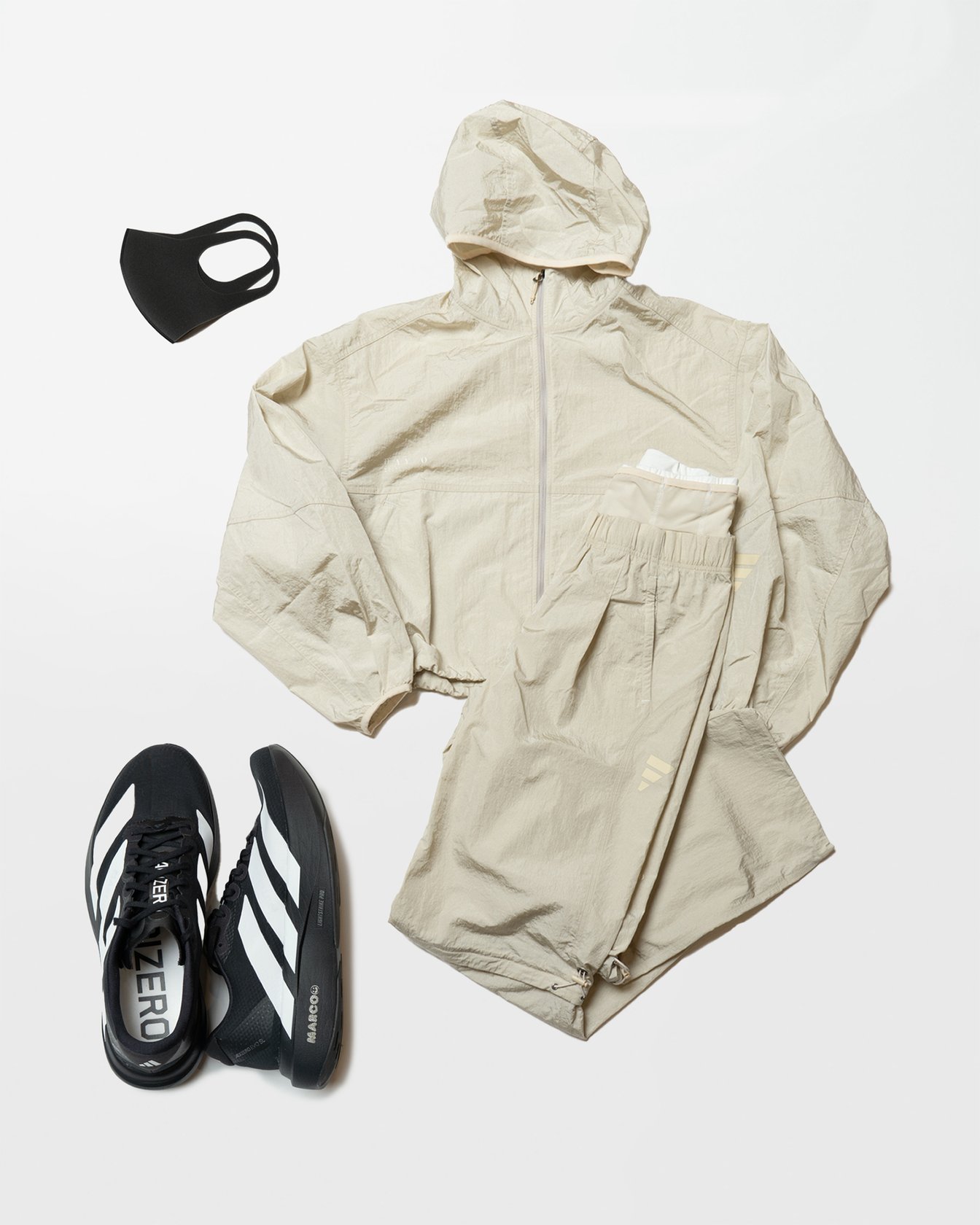 アイボリーのセットアップと黒いランニングシューズ、マスク