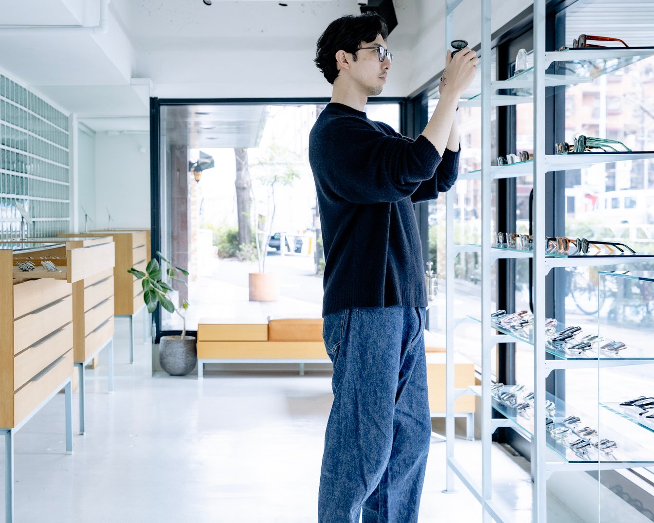 眼鏡を眺めるayameデザイナーの今泉悠