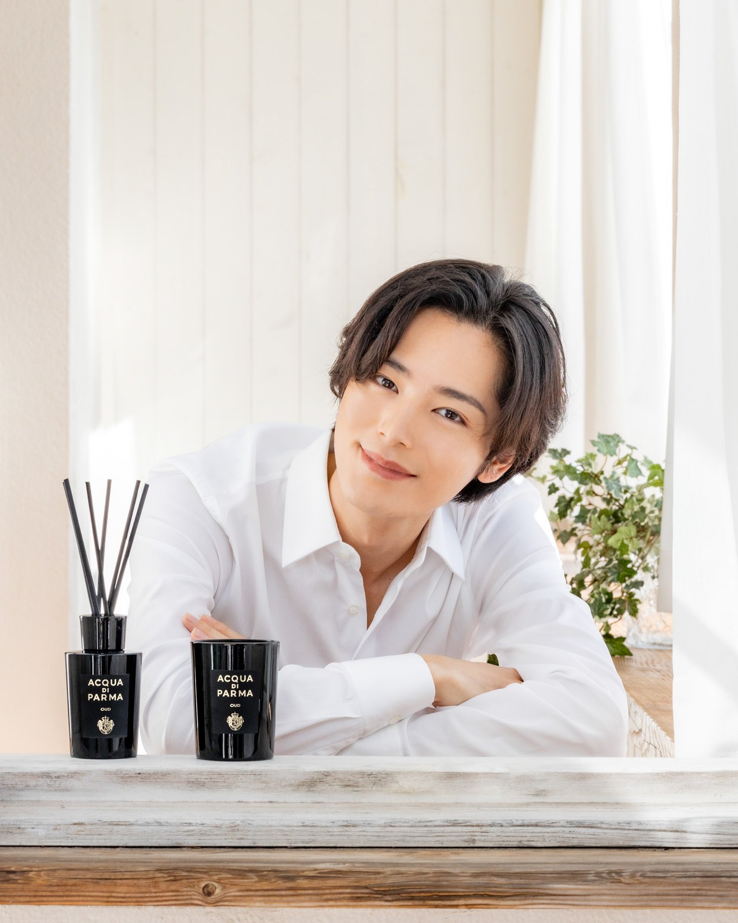 微笑む男性と黒い容器に入ったディフューザーとキャンドル