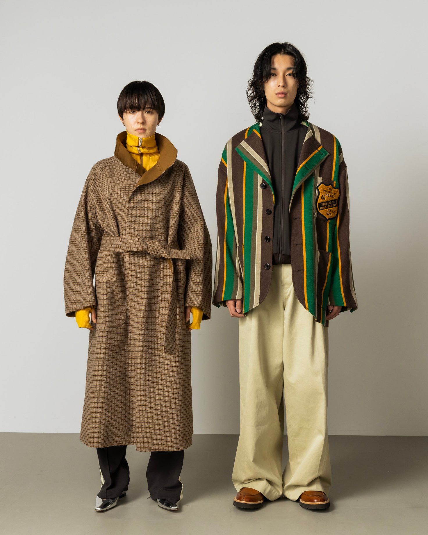 ベージュのコートを着用した女性モデルとトラッドジャケットを着た男性モデル