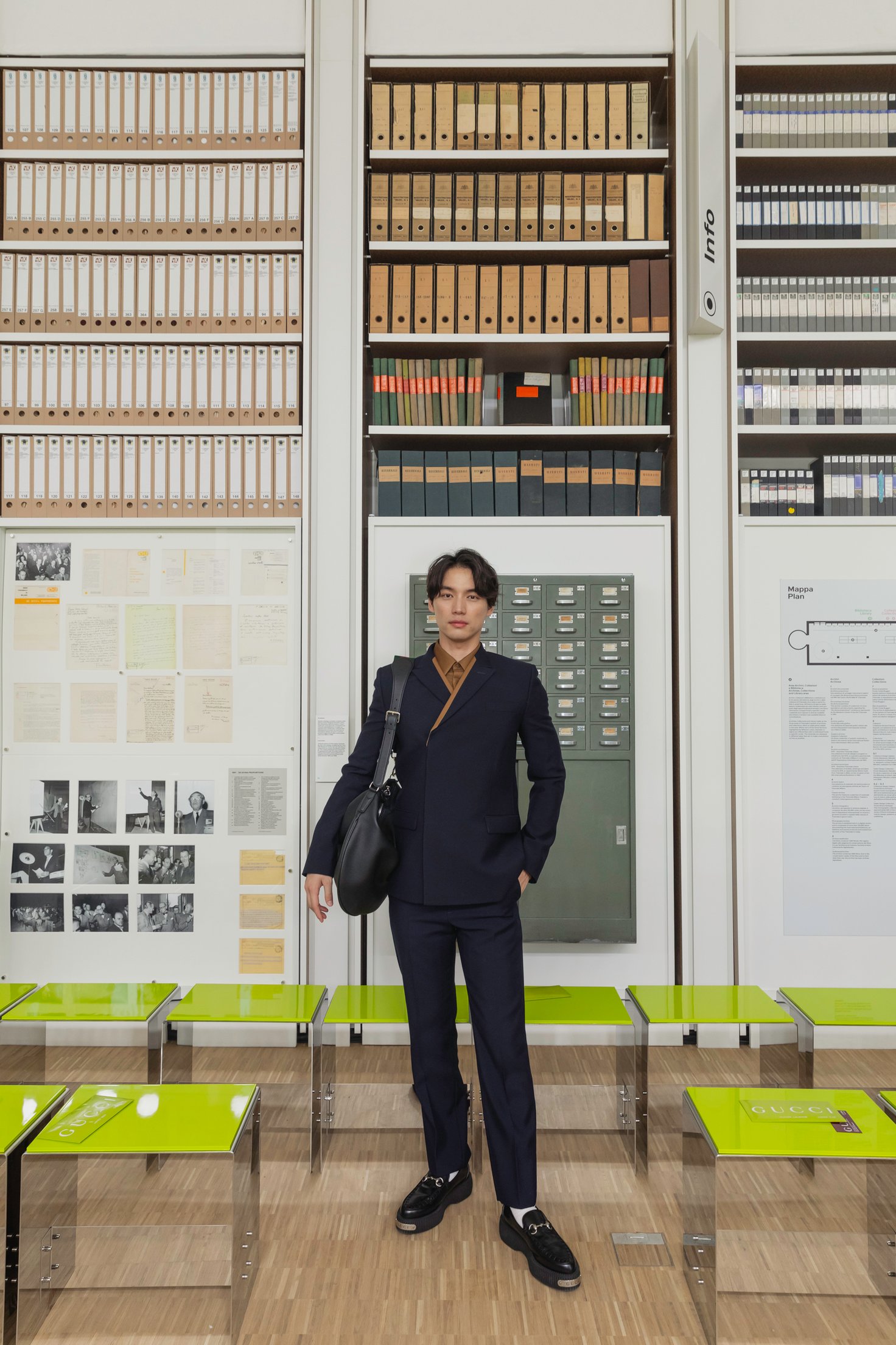 本棚の前に立つスーツを着た男性