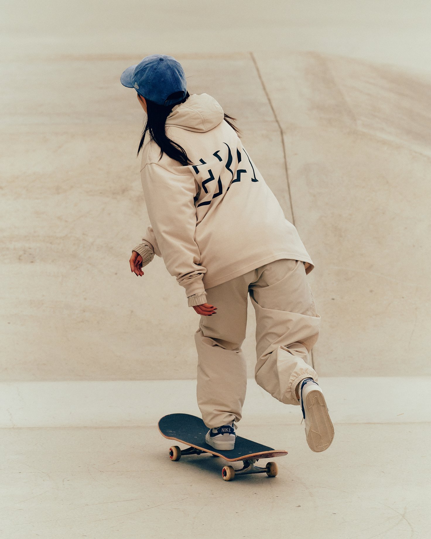 スケートボードに乗って滑る西村碧莉の後ろ姿全身